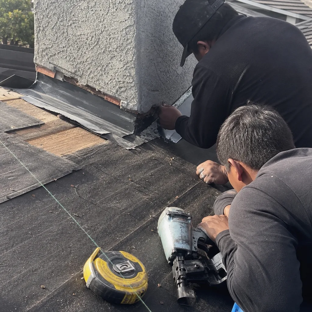 Roofers installing professional chimney flashing and roofing materials on a home.